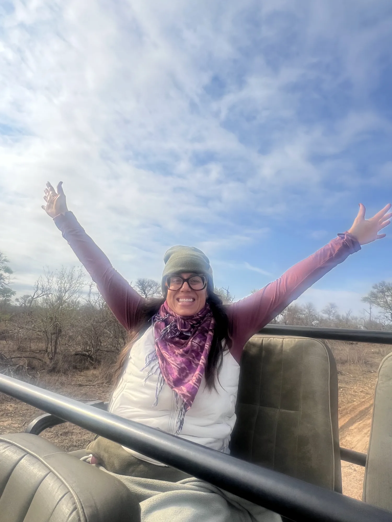 Amanda Lee with arms raised, laughing, on a safari drive in Africa